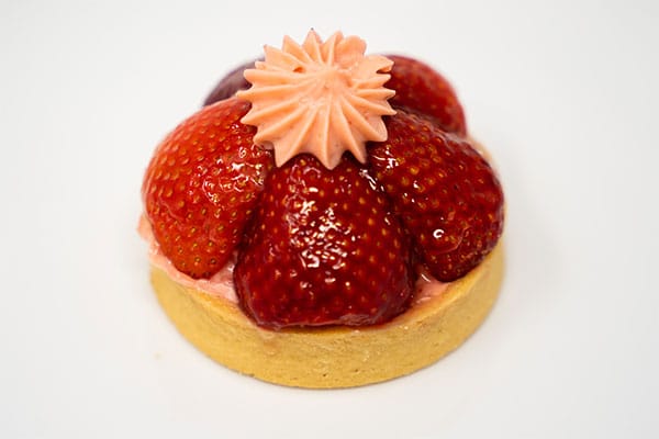 Individual strawberry tart with glazed whole strawberries and a piped pink cream rosette