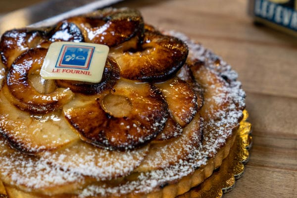 Whole apple tart with caramelized apple slices arranged in a rose shape, dusted with powdered sugar